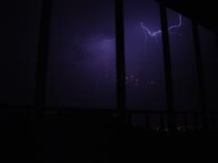 A photo of lightning, reflected lava lamps, iron security bars, and faint city lights